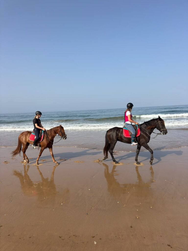 Horse riding in Agadir — two riders on the wet sand with the turquoise Atlantic behind them