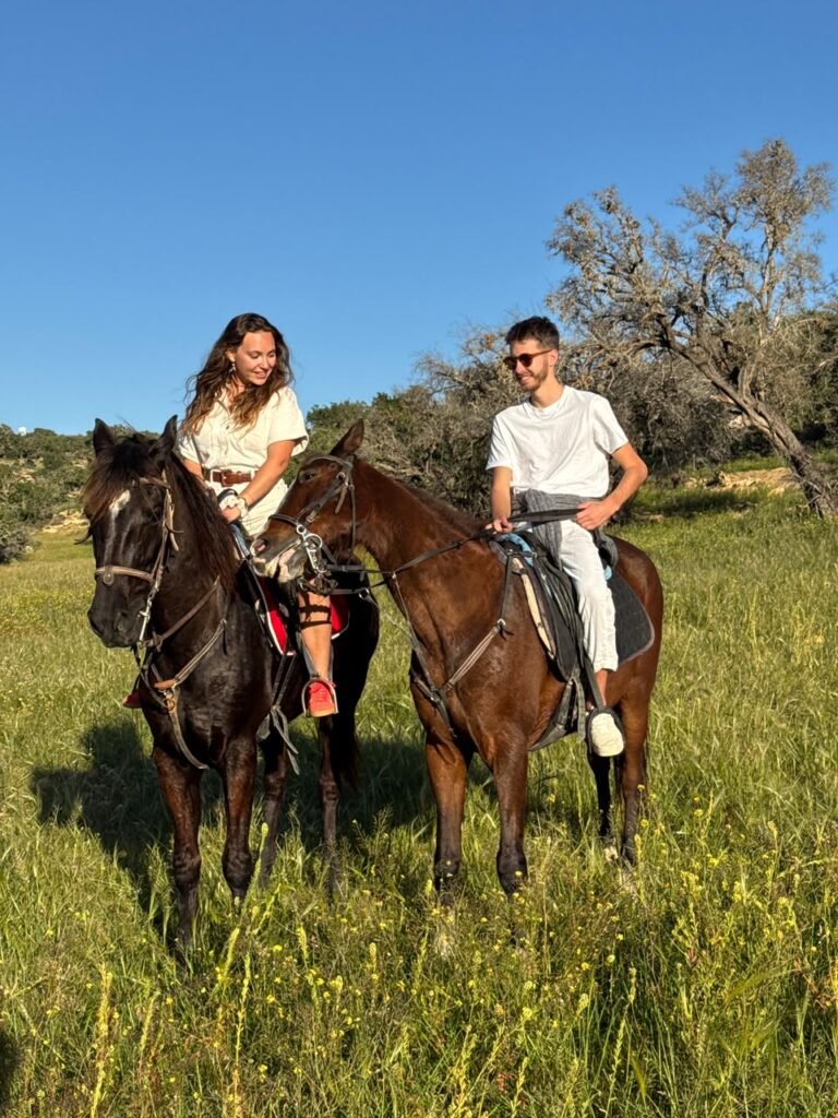 Half-day horse ride near Tamraght — two riders crossing green countryside on the forest and beach route