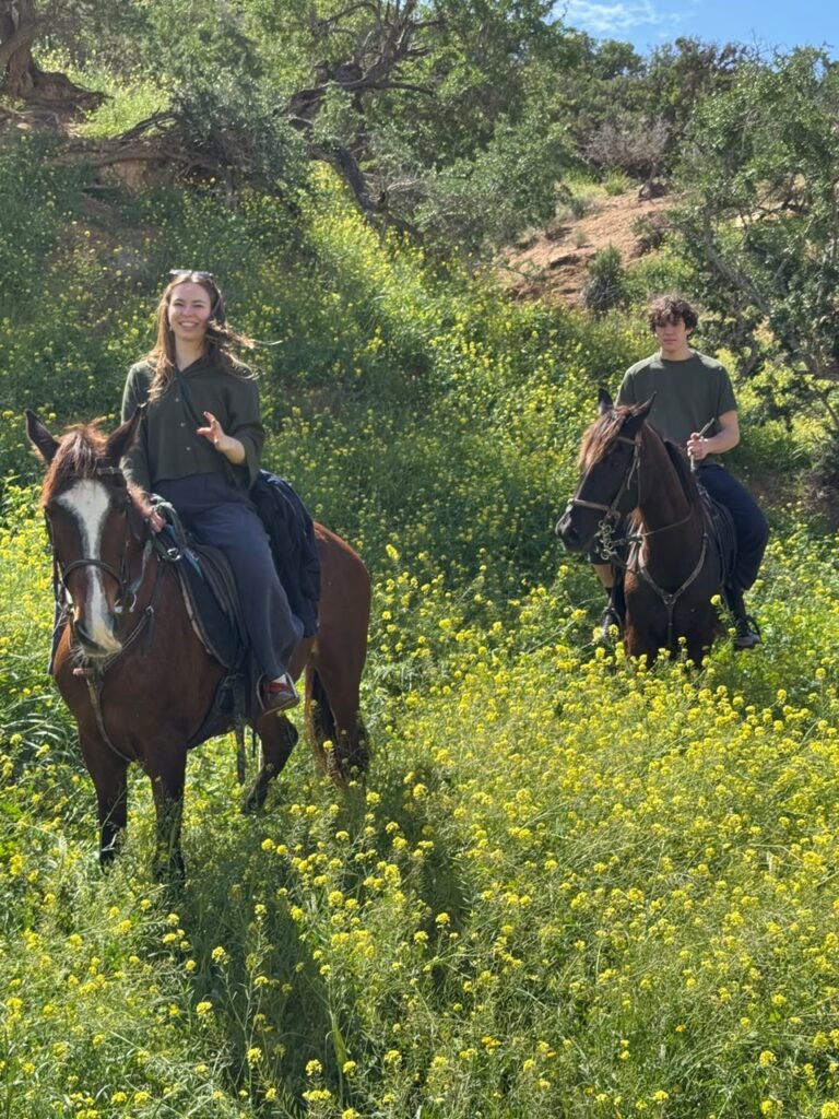 Horse riding near Agadir — two riders crossing the green countryside inland from the coast